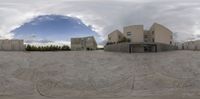 a fish - eye lens view of the courtyard and entrance to a residential complex with some buildings in the background