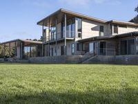 a big house sitting on a hillside next to a forest and a hill side field