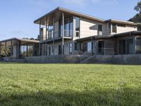 a big house sitting on a hillside next to a forest and a hill side field