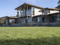 a big house sitting on a hillside next to a forest and a hill side field