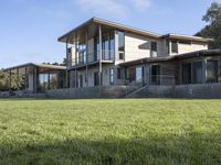 a big house sitting on a hillside next to a forest and a hill side field