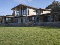 a big house sitting on a hillside next to a forest and a hill side field