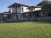 a big house sitting on a hillside next to a forest and a hill side field