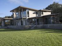 a big house sitting on a hillside next to a forest and a hill side field