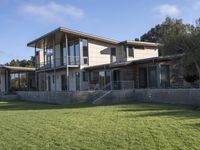 a big house sitting on a hillside next to a forest and a hill side field