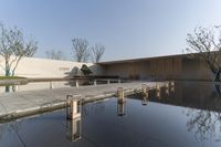 the entrance to the building is reflected in a pond of water and water screechers