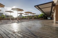 an empty patio area with tables and umbrellas above it and sunbeams over the courtyard