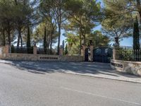 the driveway of the villa is quiet on this sunny day that it is very shaded with trees and stone,