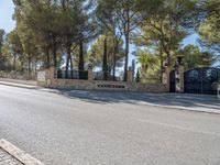 the driveway of the villa is quiet on this sunny day that it is very shaded with trees and stone,