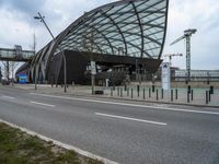 an open, curved building sitting next to a river with lots of traffic passing by