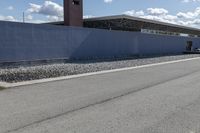 a building is on the side of a road with gravel and rocks around it and a truck driving by it