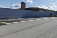 a building is on the side of a road with gravel and rocks around it and a truck driving by it