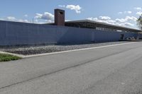 a building is on the side of a road with gravel and rocks around it and a truck driving by it