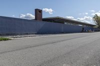 a building is on the side of a road with gravel and rocks around it and a truck driving by it