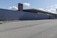 a building is on the side of a road with gravel and rocks around it and a truck driving by it