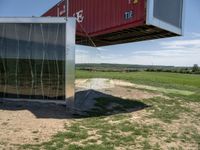 a metal building is connected to an open green field and a red one with its roof attached