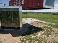 a metal building is connected to an open green field and a red one with its roof attached