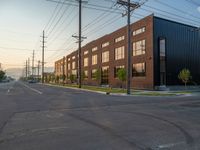 an empty street in front of a large red brick building on the other side of the road is a street light that has a line for motorists