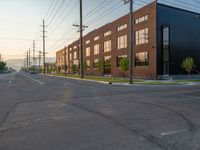 an empty street in front of a large red brick building on the other side of the road is a street light that has a line for motorists