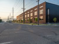 an empty street in front of a large red brick building on the other side of the road is a street light that has a line for motorists