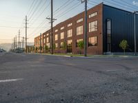 an empty street in front of a large red brick building on the other side of the road is a street light that has a line for motorists