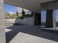 an outdoor courtyard with concrete walls and a bench with a red bag in it and the stairs up and mountains behind