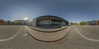 a spherical panorama of an empty parking lot with a school building in the background and a person in the middle of one shot