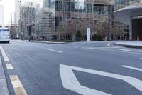 a bus is riding on an empty city street near a business building in the distance