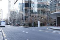 a bus is riding on an empty city street near a business building in the distance