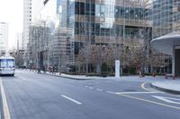 a bus is riding on an empty city street near a business building in the distance