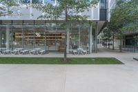 a large glass walled building has many tables and chairs on it's patio area