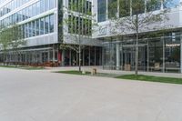 a glass building with tables and chairs and a bench in the park area next to it