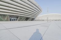 a view from inside an empty building that is white and has a curved walkway in front of it