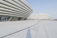 a view from inside an empty building that is white and has a curved walkway in front of it