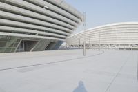 a view from inside an empty building that is white and has a curved walkway in front of it