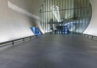 a hallway with benches and long windows looking at the outside of a building that is glass