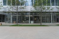 a building with some glass walls and a tree in front of it with the door open