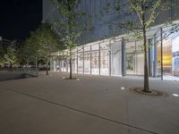 an outside shot of a building with trees in front of it at night time with the sky darkened