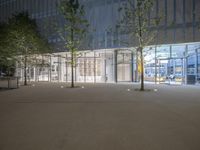 an outside shot of a building with trees in front of it at night time with the sky darkened