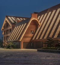 a large brown and black building with windows at dusk with the lights on it's side