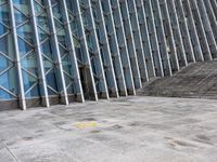 the person walking on a sidewalk near a very large building in front of some stairs