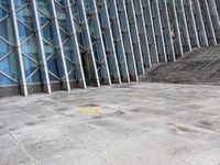 the person walking on a sidewalk near a very large building in front of some stairs