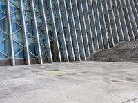 the person walking on a sidewalk near a very large building in front of some stairs