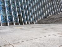 the person walking on a sidewalk near a very large building in front of some stairs