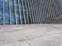 the person walking on a sidewalk near a very large building in front of some stairs