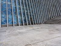 the person walking on a sidewalk near a very large building in front of some stairs