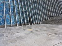 the person walking on a sidewalk near a very large building in front of some stairs