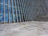 the person walking on a sidewalk near a very large building in front of some stairs