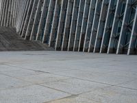 the person walking on a sidewalk near a very large building in front of some stairs