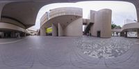 a fish eye lens captures a view of a shopping center, an entrance, and a brick structure with decorative mosaics